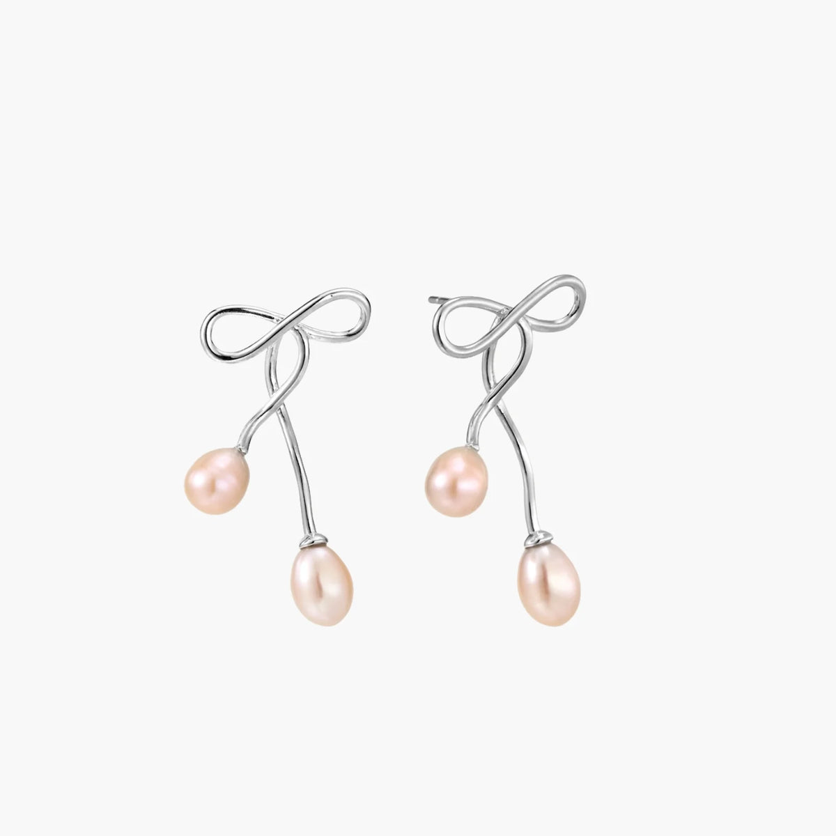 Rhodium-plated silver earrings with organic vine curves and two peachy freshwater pearls on cream background