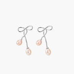 Rhodium-plated silver earrings with organic vine curves and two peachy freshwater pearls on cream background
