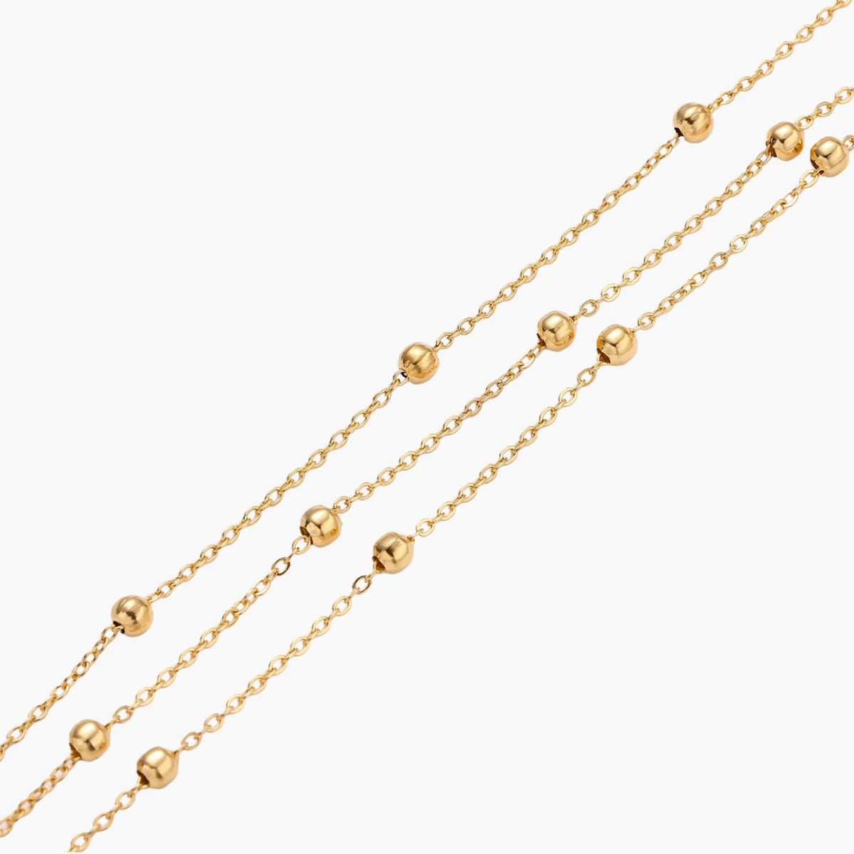 Three-strand gold-plated bracelet with clustered ball beads and adjustable clasp on cream background