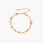 Three-strand gold-plated bracelet with clustered ball beads and adjustable clasp on cream background