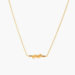 Dainty 18K gold plated necklace with infinity knot pendant on delicate chain against white background