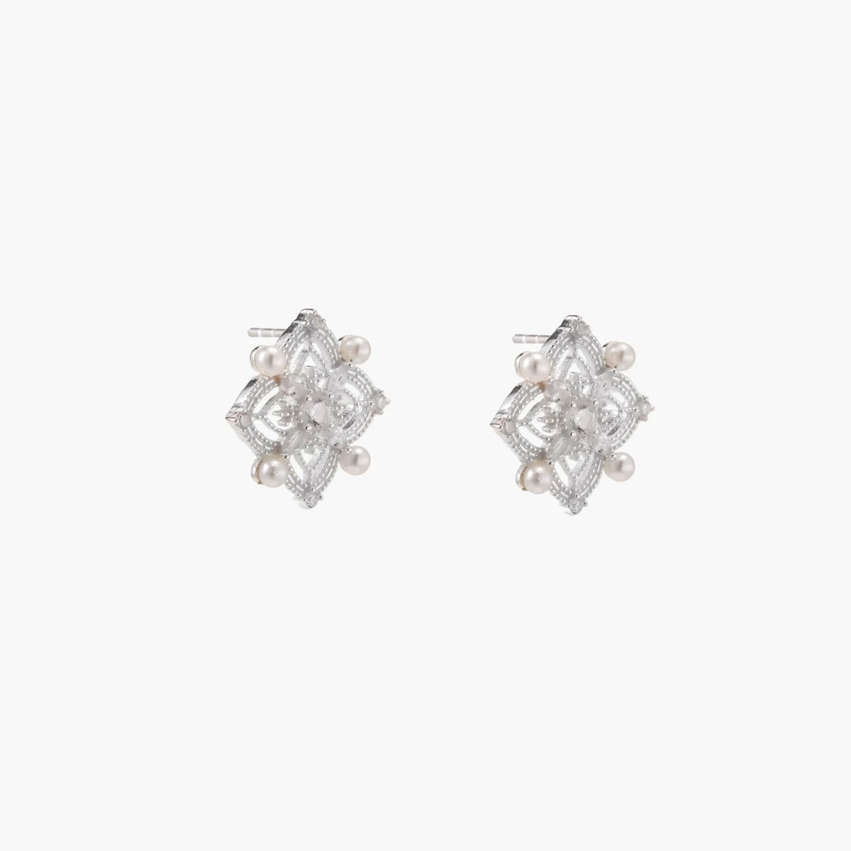Ornate sterling silver stud earrings with mandala-inspired filigree pattern and four freshwater pearls on beige background