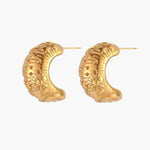Gold-plated chunky hoop earrings with sun and star engravings on white background, showing detailed celestial pattern work.