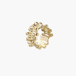 Gold-plated brass ring with sculptural petal-like elements in a wide band design on beige background