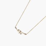 Gold-plated curved bar necklace with diamond accents on delicate chain against cream background