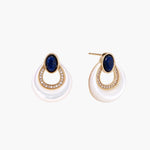 Gold drop earrings with oval lapis lazuli, crystal-paved frame, and iridescent mother-of-pearl teardrop on cream background