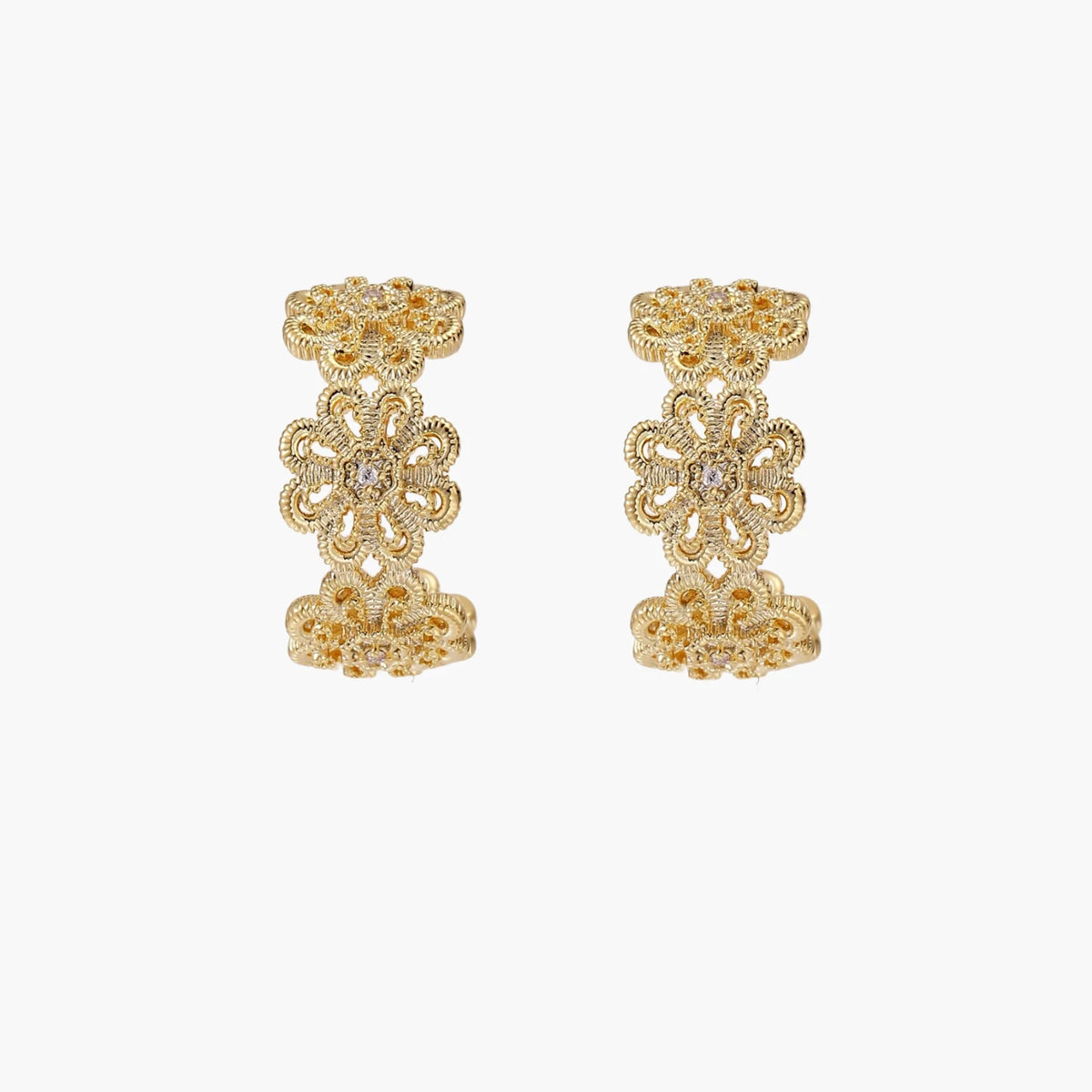 Gold hoop earrings with intricate three-dimensional floral filigree pattern in 14K gold plated brass on cream background