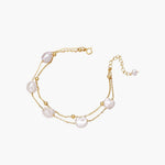 Double-strand gold bracelet with irregular baroque pearls and smooth freshwater pearls on cream background.
