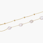 Double-strand gold bracelet with irregular baroque pearls and smooth freshwater pearls on cream background.