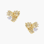 Pair of sculptural gold-plated wing stud earrings with zirconia stones on cream background, showing dimensional feather design